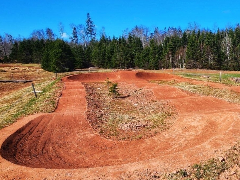 Pump track, Brookvale, PEI View of pump track in foreground with trees and blue sky in background