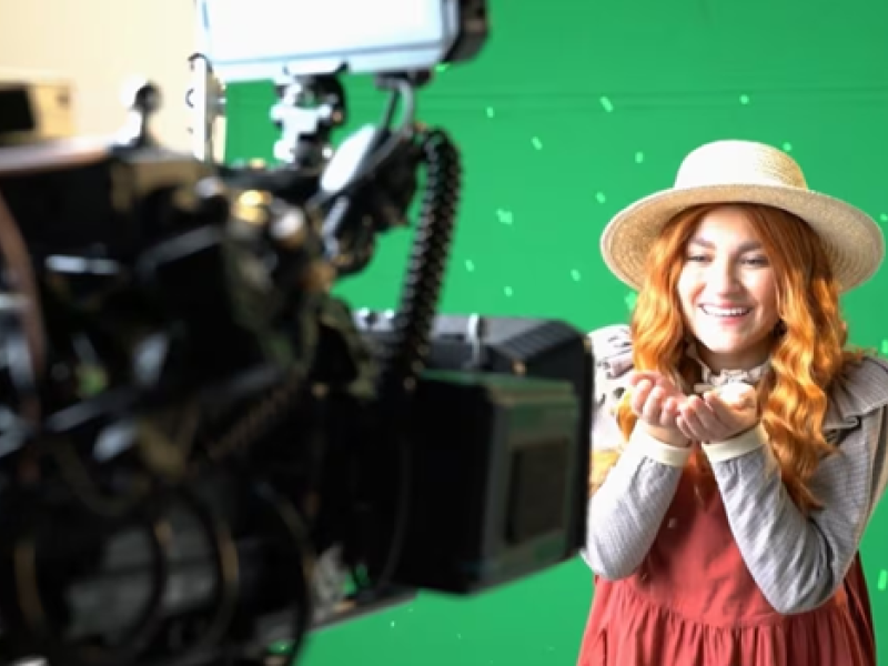 Michela Luci in character a Anne Shirley in front of video camera on a green screen