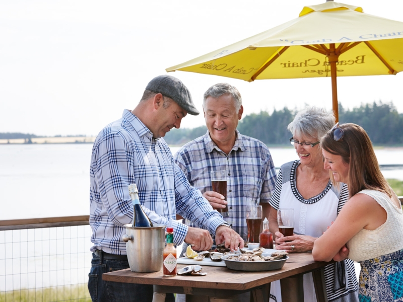 Waiter serves oysters on a restaurant deck to a party of three 