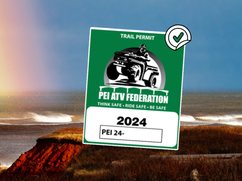 Image of PEI ATV Federation Trail pass in foreground with a rainbow in the sky over PEI red cliffs in bkg