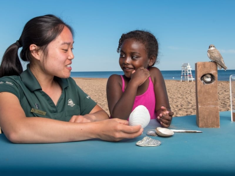 PEI National Park Parks Canada staff person interacts with young girl at the beach about beach ecology