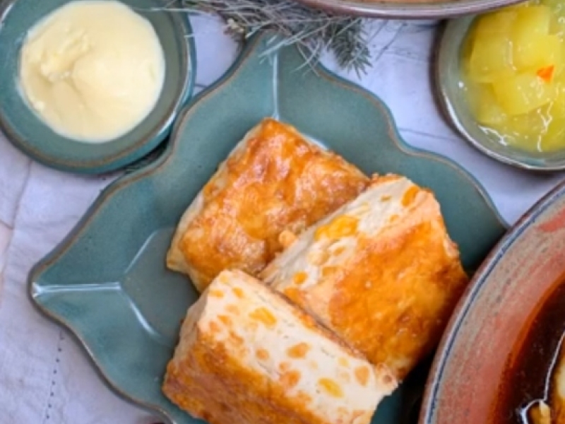 Cheddar biscuits on teal coloured plate with dish of butter and mustard pickles to the side