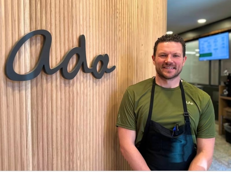 Chef Adam Look stands in front of his restaurant's signage name, ADA