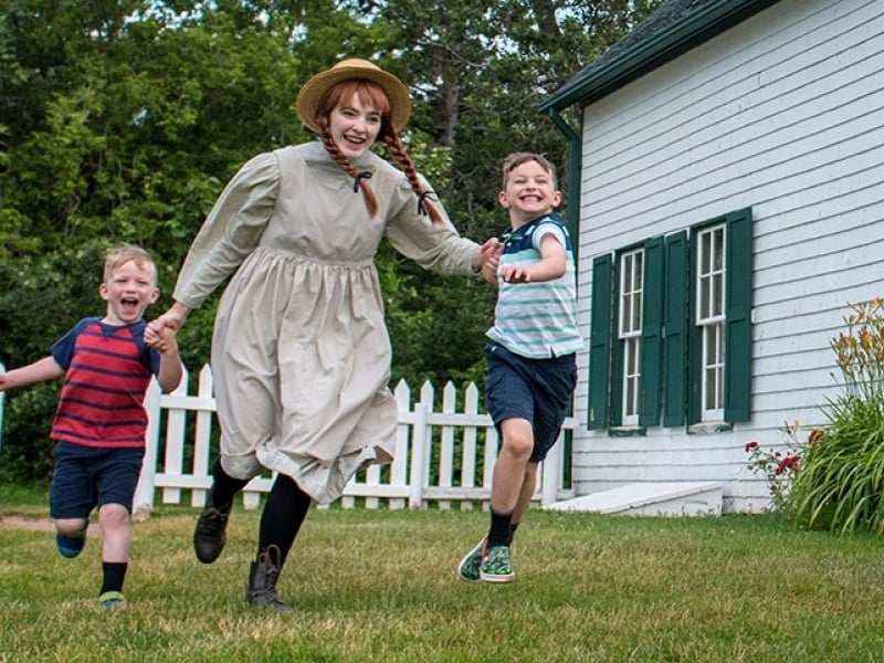 Anne of Green Gables performer plays with children on lawn of Green Gables Heritage Place