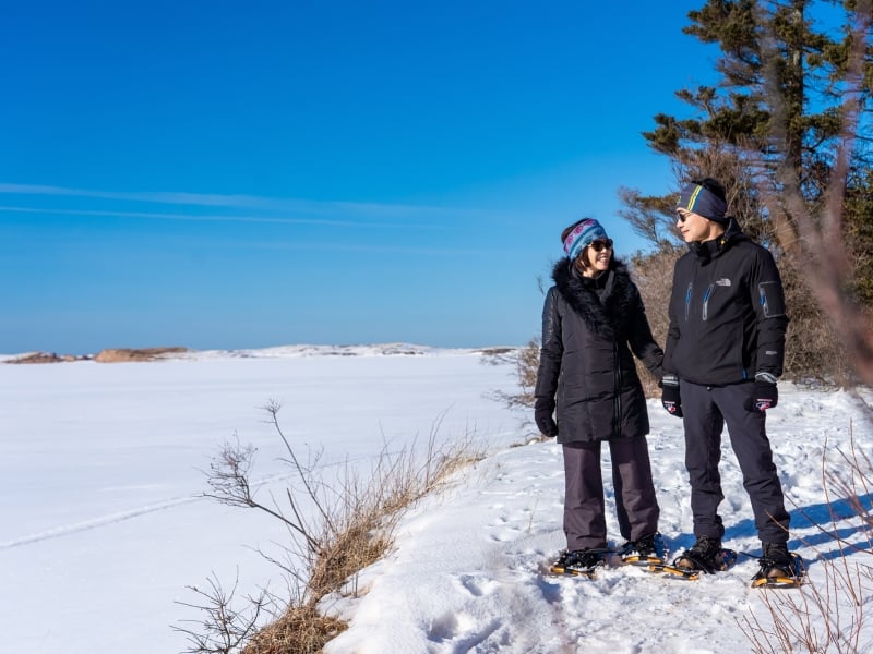 Couple snowshoe at PEI National Park in Cavendish in winter