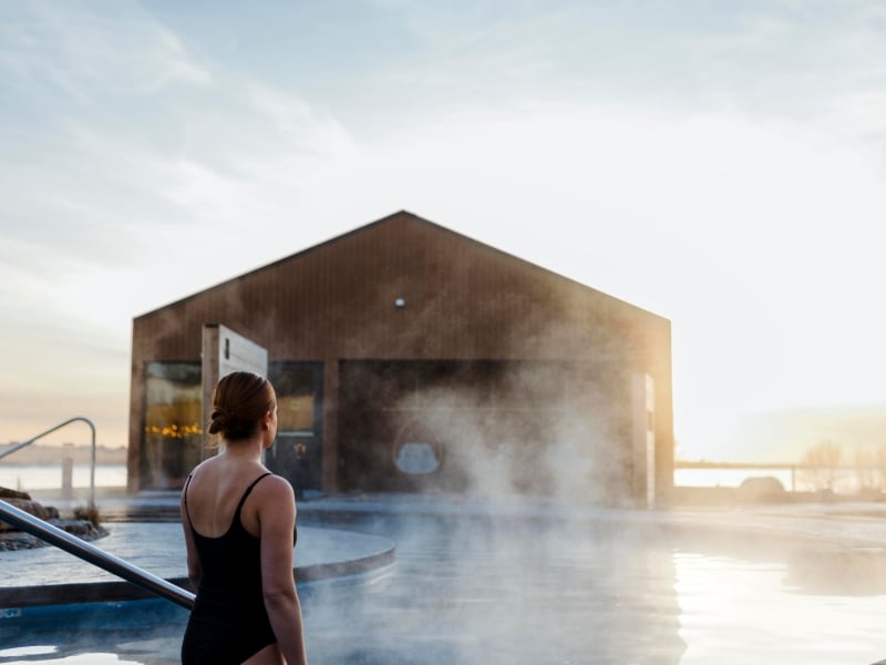 Mysa Nordic Spa Person stands in hot tub looking over St. Peter's Bay in winter