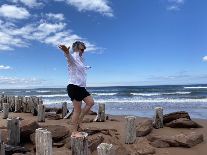 Person balances on old pier timber at Tracadie Beach