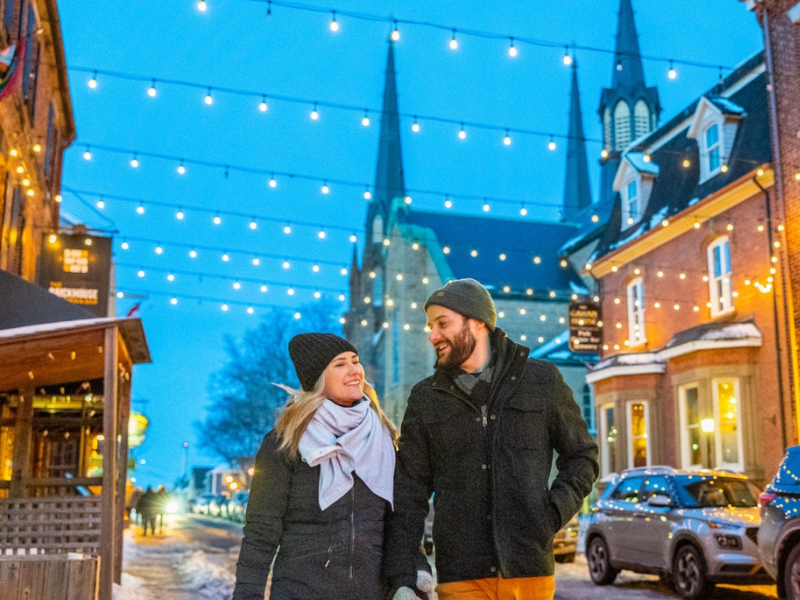 Couple walk down Sydney Street in winter under glowing strings of light