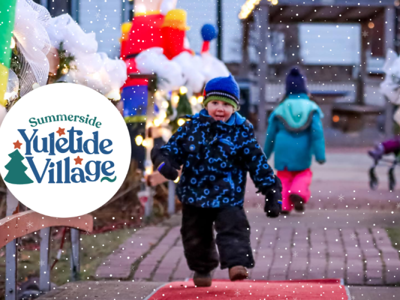 Small child in snowsuit runs through Summerside park with holiday decorations; Summerside Yuletide logo in circle