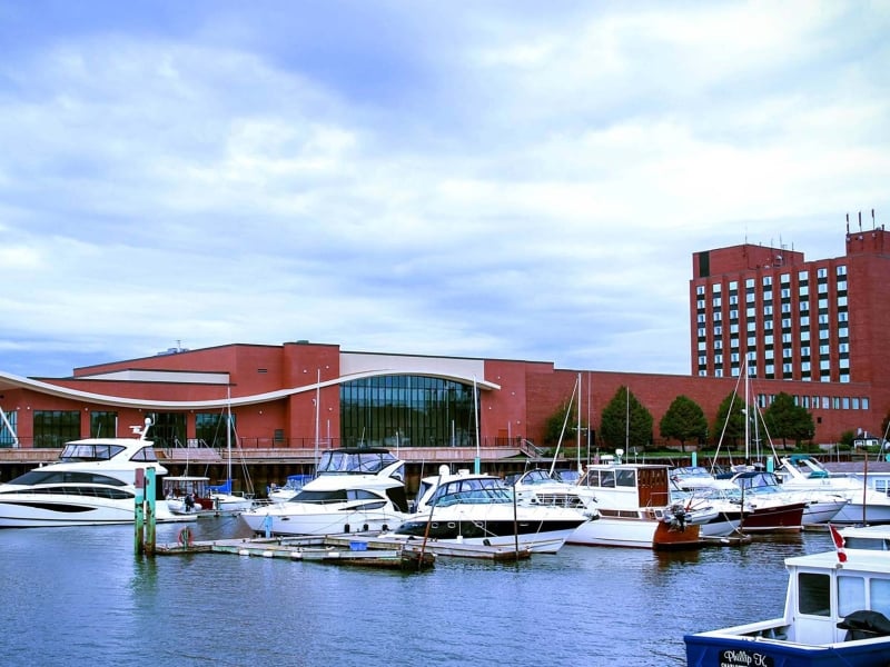 outside view of the large brick exterior of the Delta Hotel, with boats and water in for front