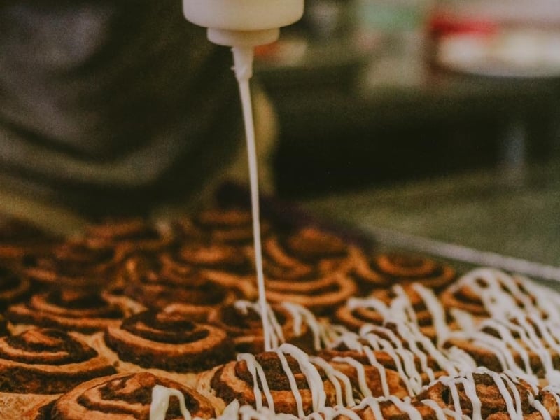 Cinnamon buns being iced in commerical kitchen