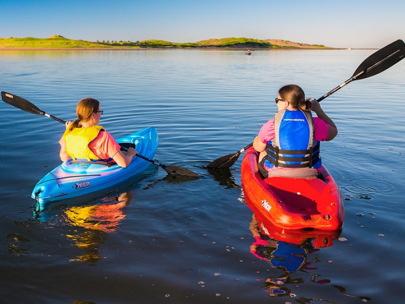 Two females kayak toward dunes near Tracadie