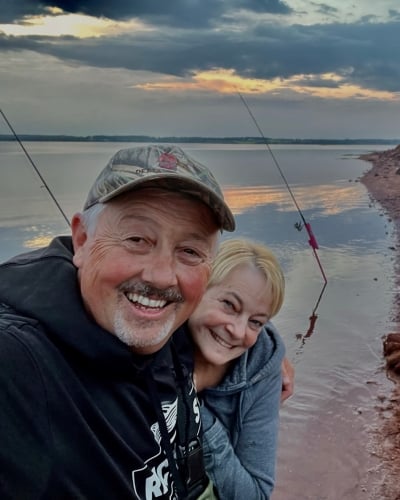 Wade and Marney MacKinnon with fishing rods in hand and a campfire on the beach