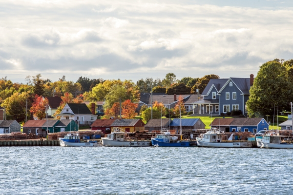 View of North Rustico harbour with fishing boats docked in foreground and fall foliage in background