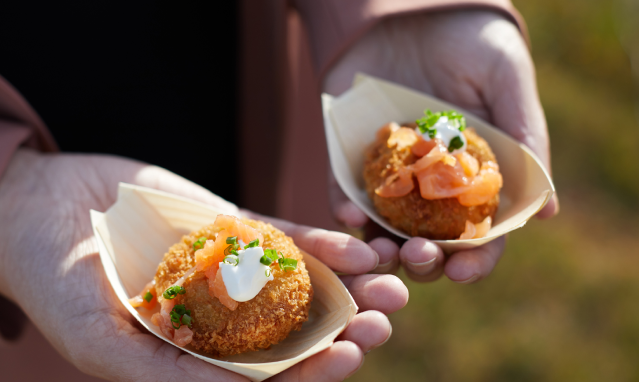 Two hands holding oysters on a half shell plate