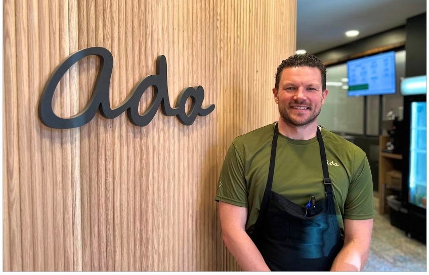 Chef Adam Look stands in front of his restaurant's signage name, ADA