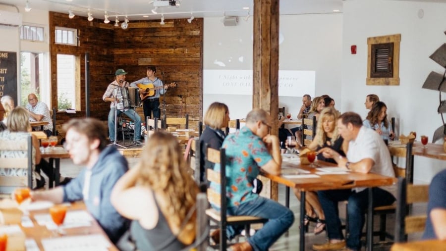 Guests sit at tables with two musicians playing in background at Lone Oak Brew Pub