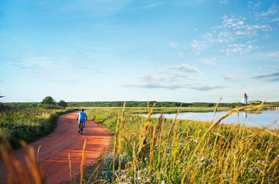 Lone cyclist on red dirt road to St. Peters Lighthouse in summer