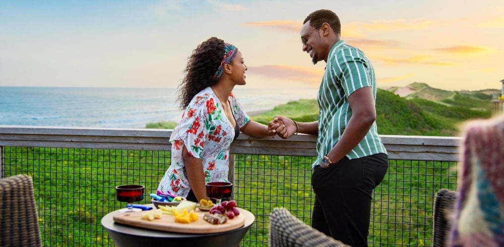 Couple watch sunset from deck of seaside cottage 