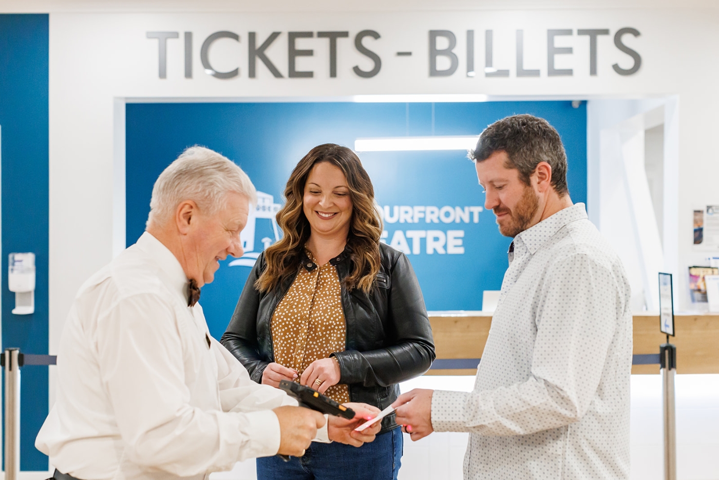 Two patrons have tickets scanned by volunteer usher