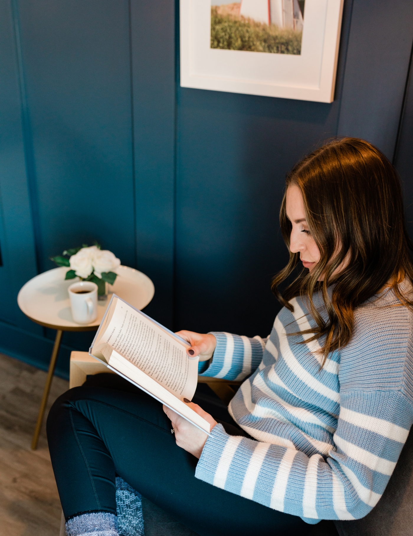 Woman sitting with a cup of tea and reading a book