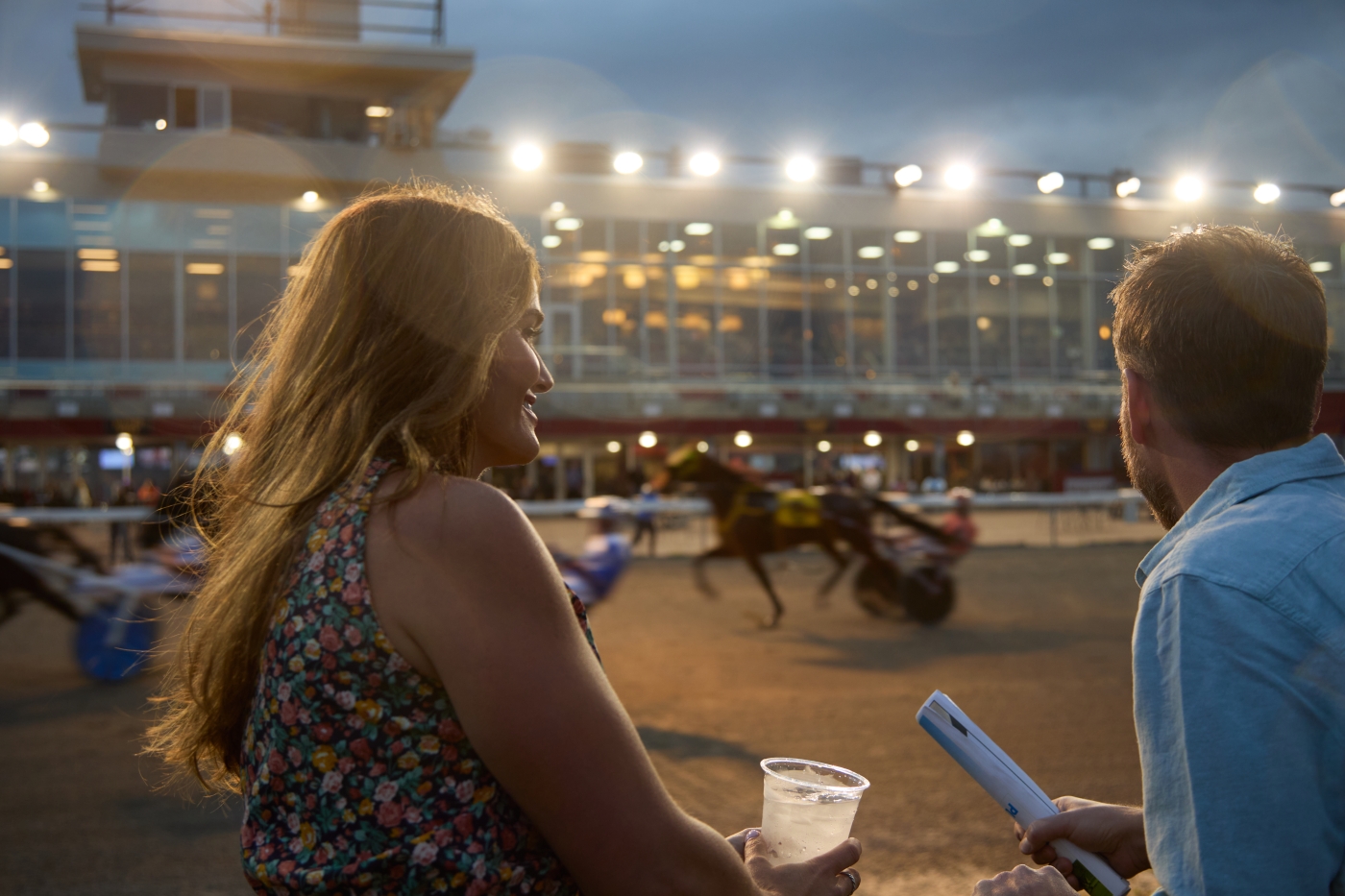 Couple looking over fence and watching horse race